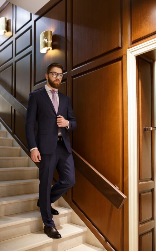 Image of serious concentrated bearded young businessman on ladder. Looking aside.